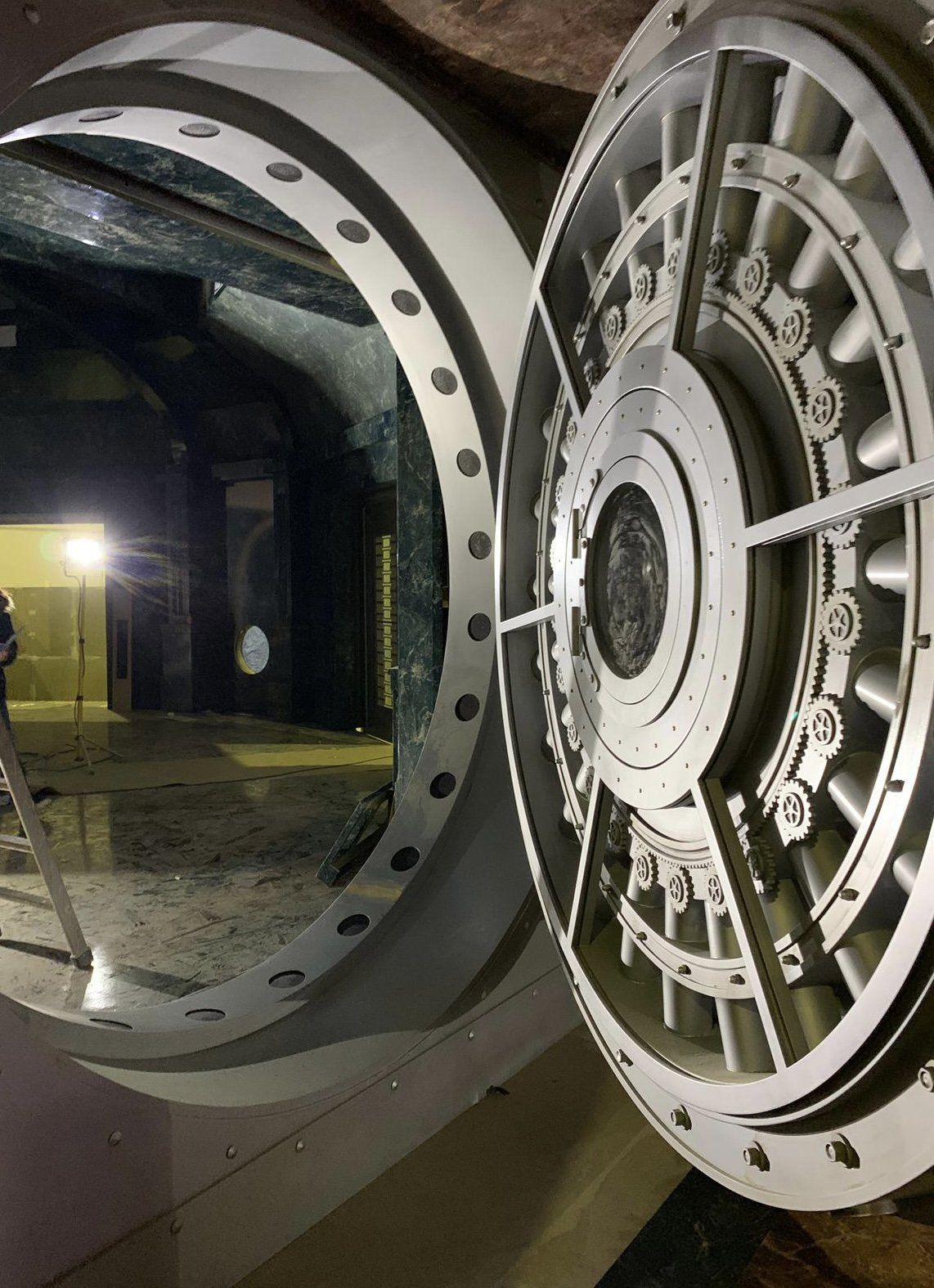 Un hombre está parado en una escalera frente a la puerta de una bóveda.