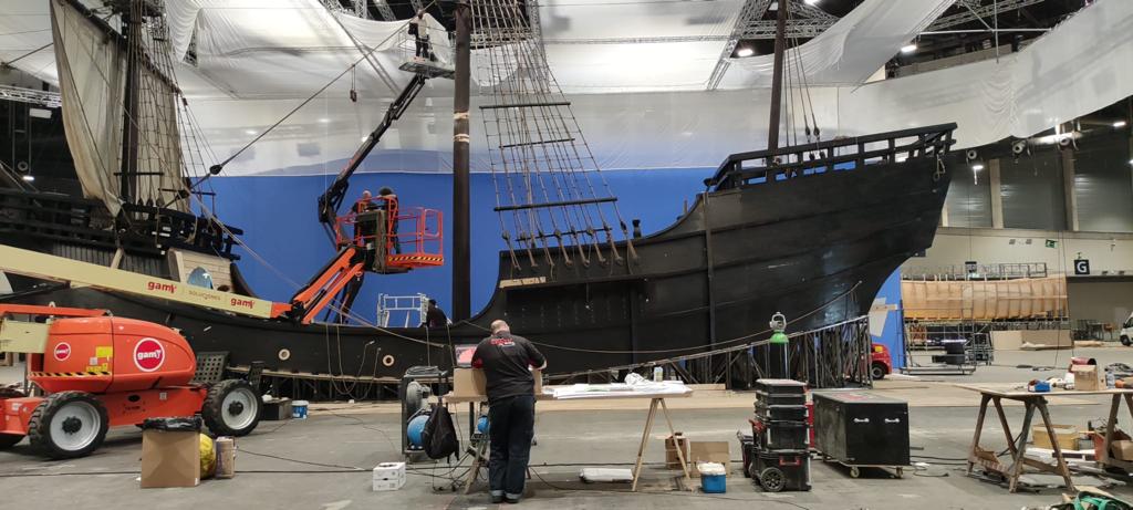 Un hombre está parado frente a un gran barco en un almacén.