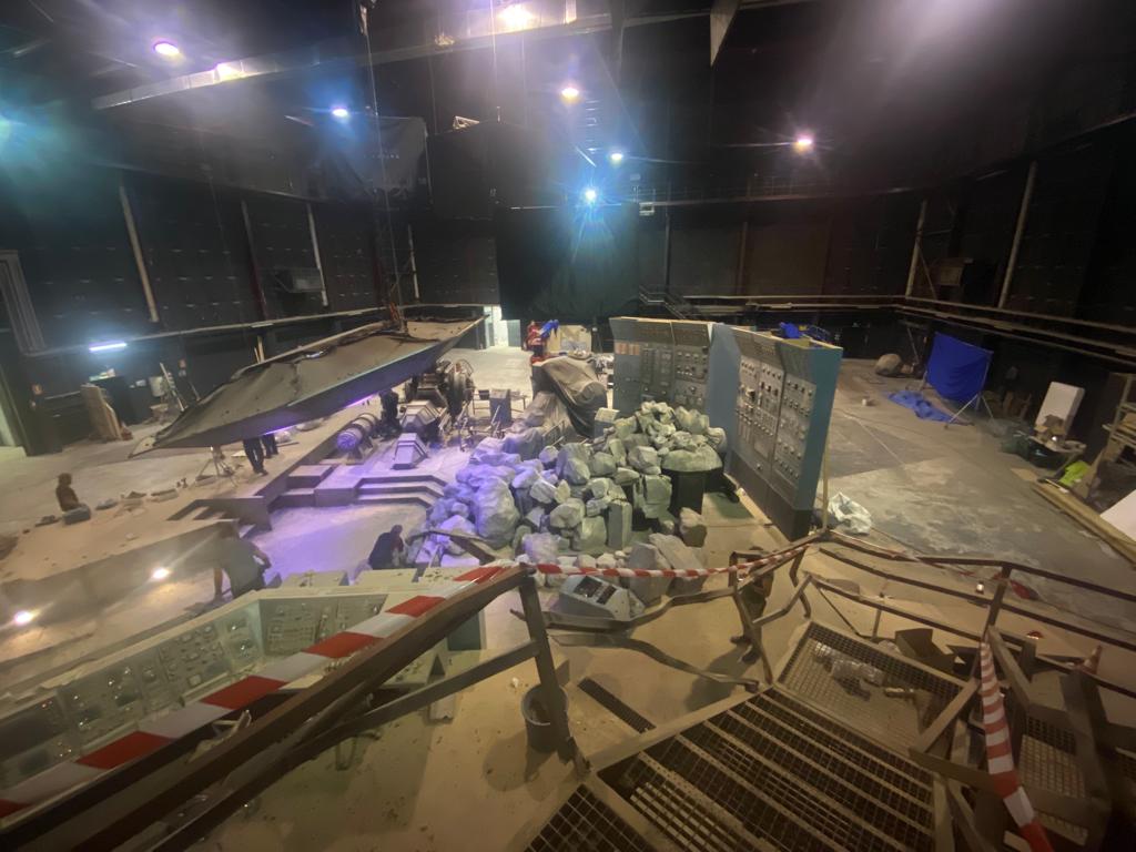 Un grupo de personas está de pie en un escenario en una habitación oscura.