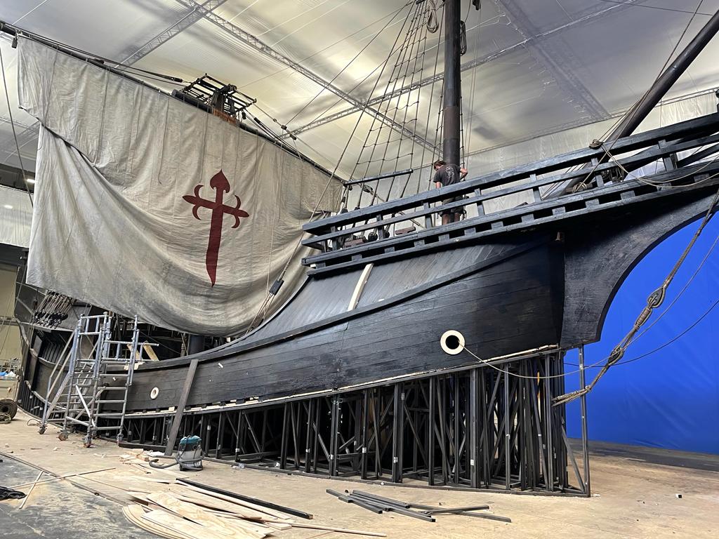 Se está construyendo un gran barco en un almacén con un fondo azul.