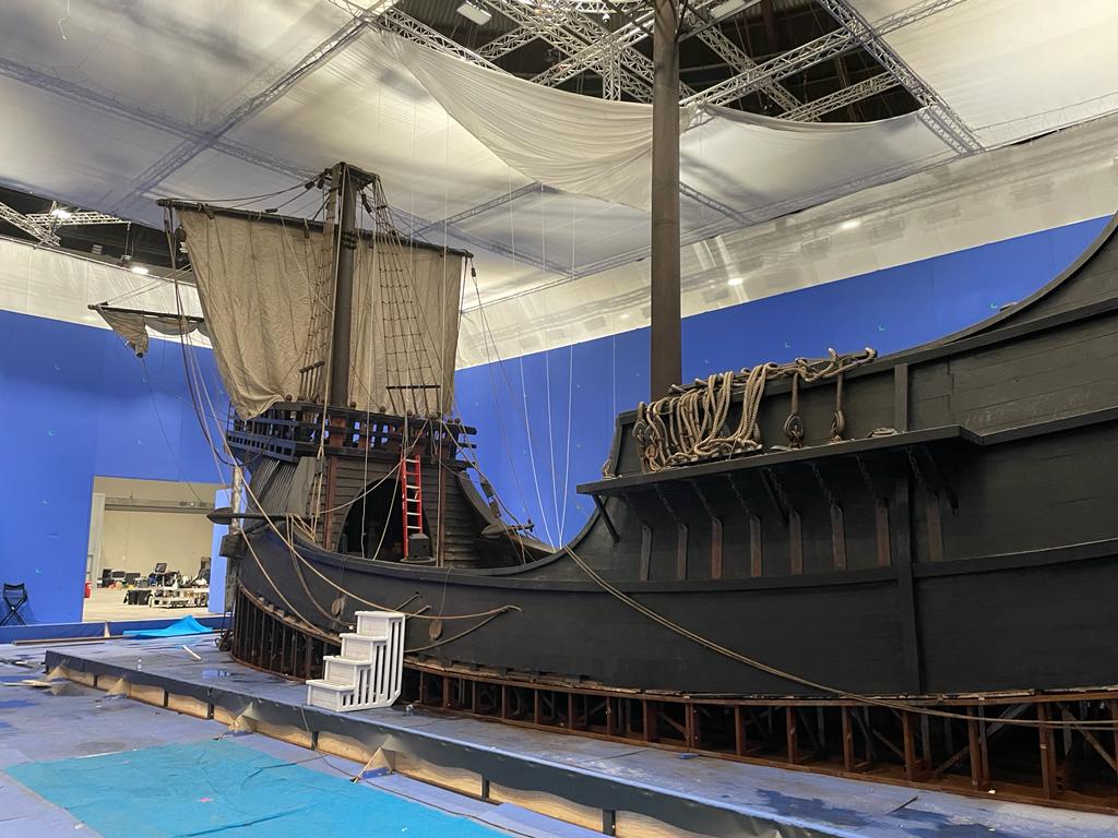 Un modelo de un barco pirata está en una habitación con un techo azul.