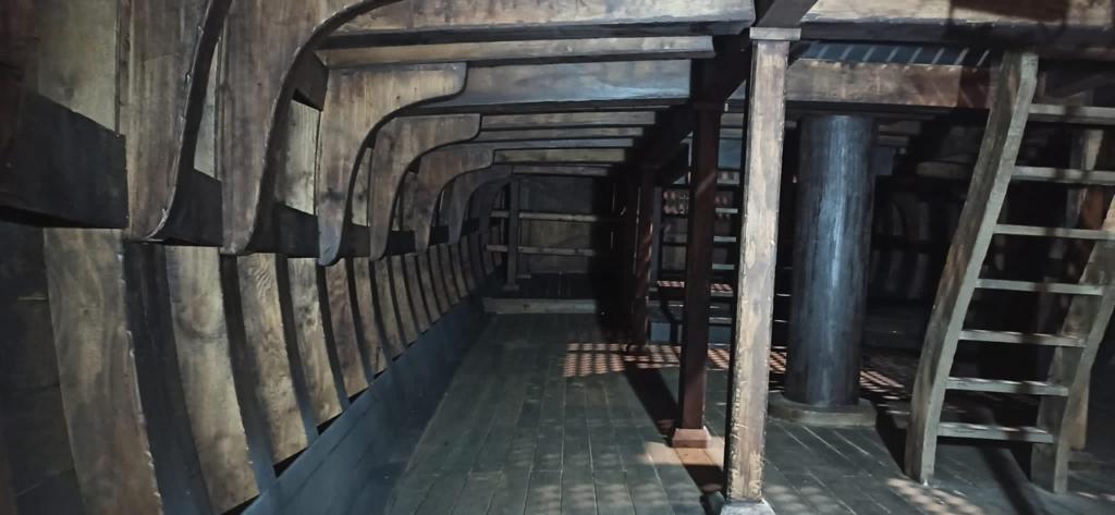 El interior de un barco con suelo de madera y escaleras.