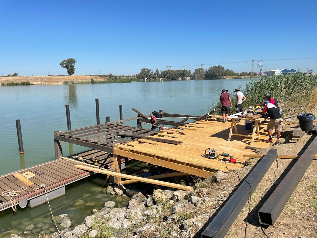Un grupo de personas está trabajando en un muelle junto a un lago.