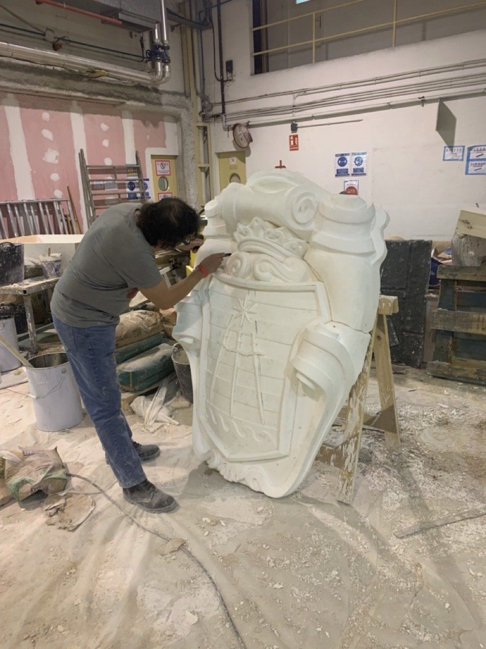 Un hombre está trabajando en una gran escultura en un taller.