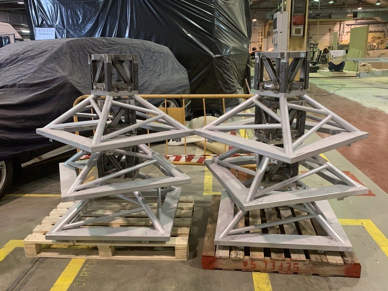 Dos estructuras metálicas se apilan una encima de otra sobre palés de madera en una fábrica.