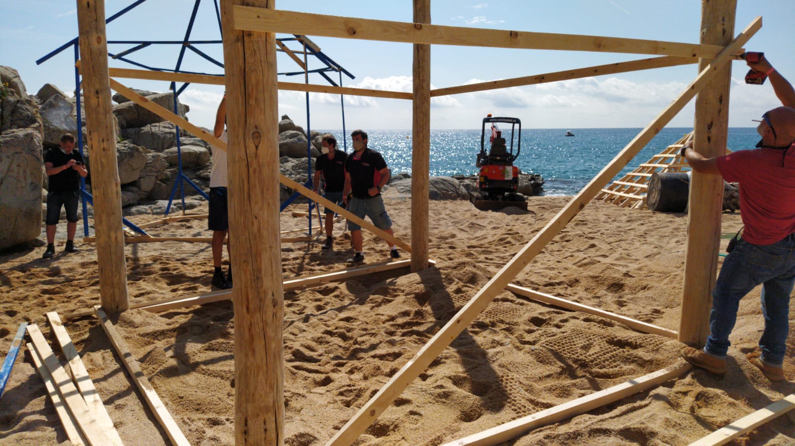 Un grupo de personas está trabajando en una estructura de madera en una playa.