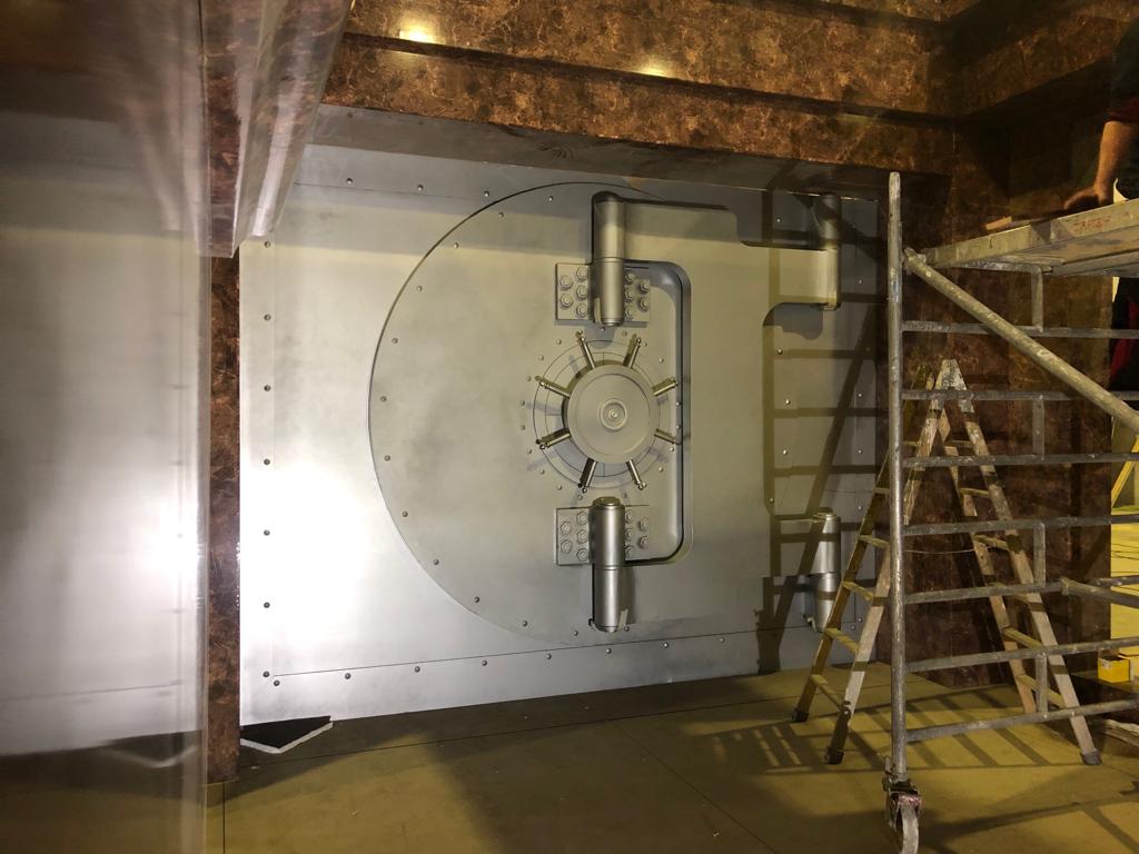 Una gran puerta de metal en una habitación con una escalera.