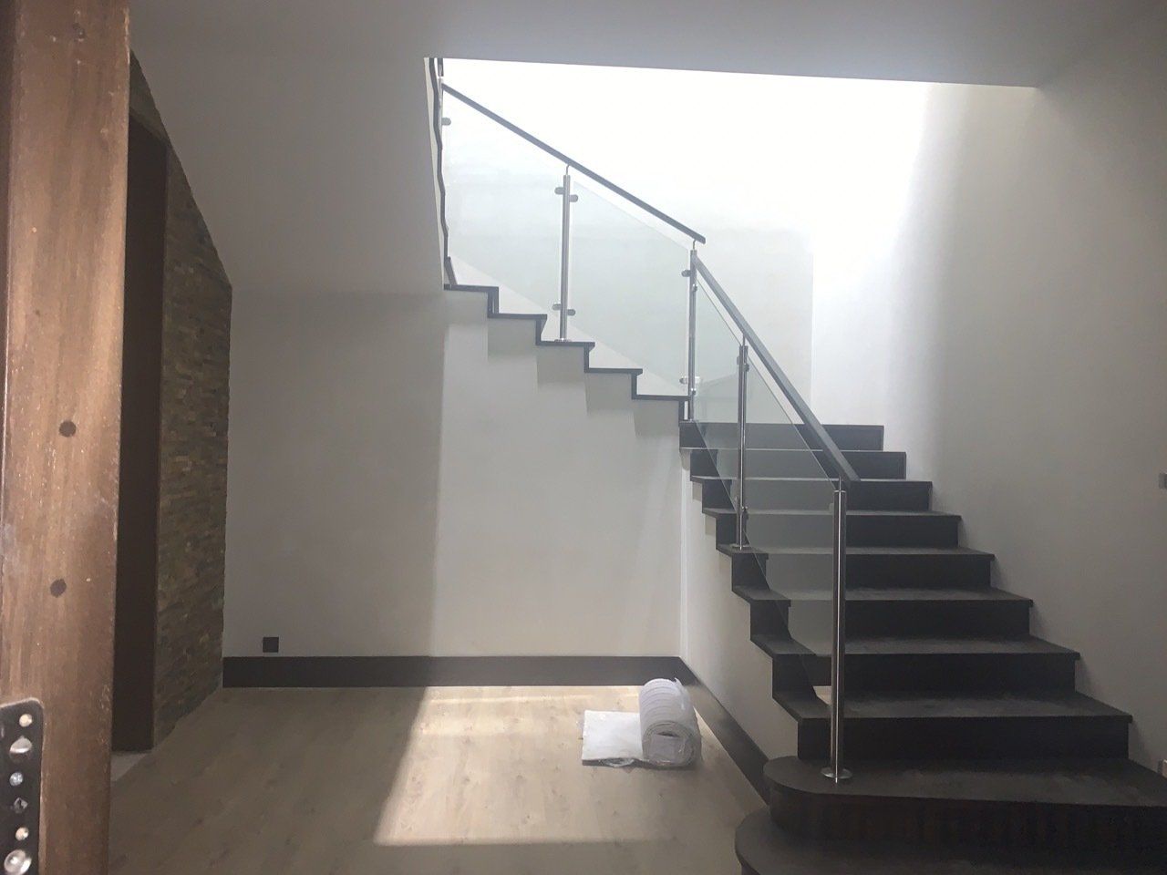 Una escalera con barandilla de cristal en una habitación vacía.