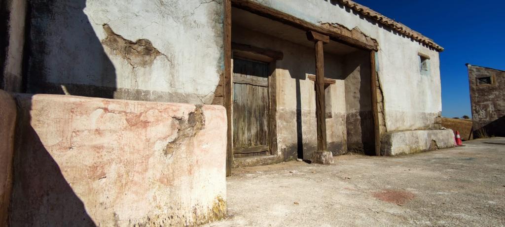 Un edificio blanco con un porche de madera y un cielo azul al fondo.