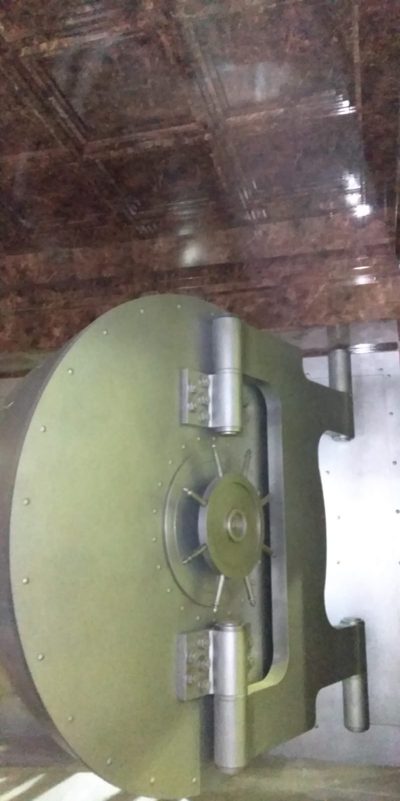 Una puerta de bóveda verde se encuentra encima de un piso de mármol.