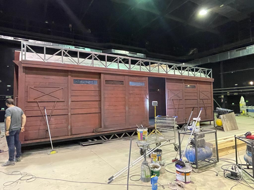 Un hombre está parado frente a un gran edificio de madera.