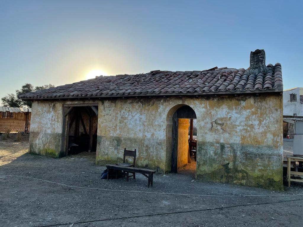 Un edificio antiguo con techo de tejas y un banco delante.