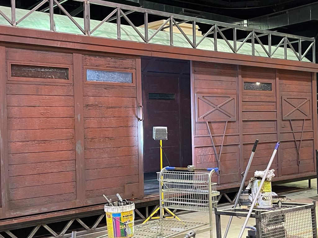 Se está pintando un vagón de tren en una habitación con muchas herramientas.