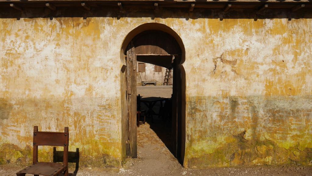 Una silla está sentada frente a una pared amarilla con una puerta.