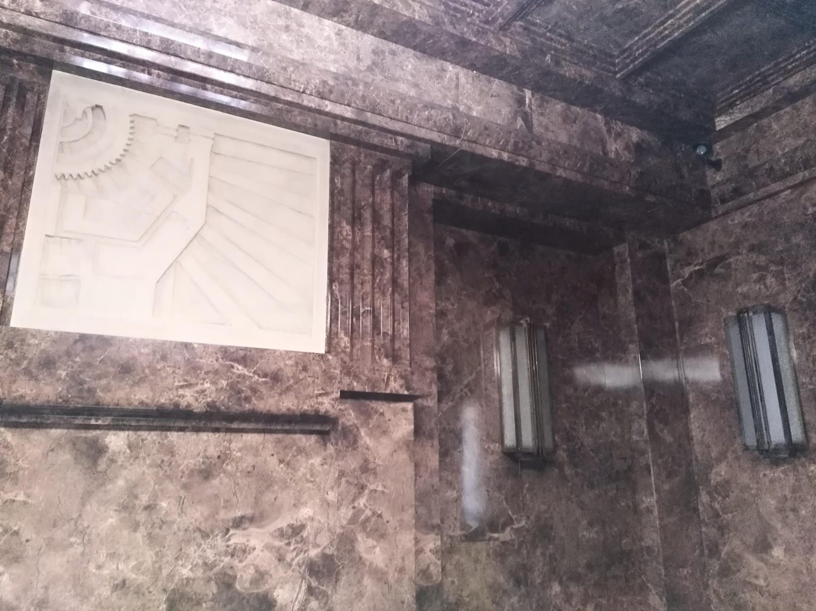 Una pared con un cuadro y una luz.