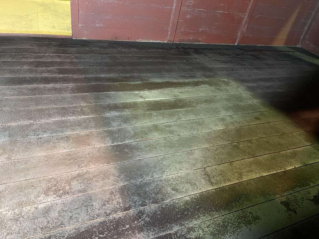 Un primer plano de un piso de madera sucio con una pared amarilla en el fondo.