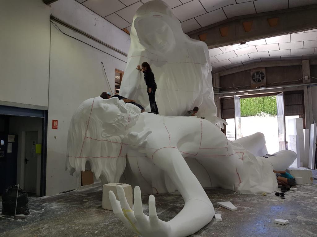 Una gran estatua blanca de una persona tendida en el suelo.