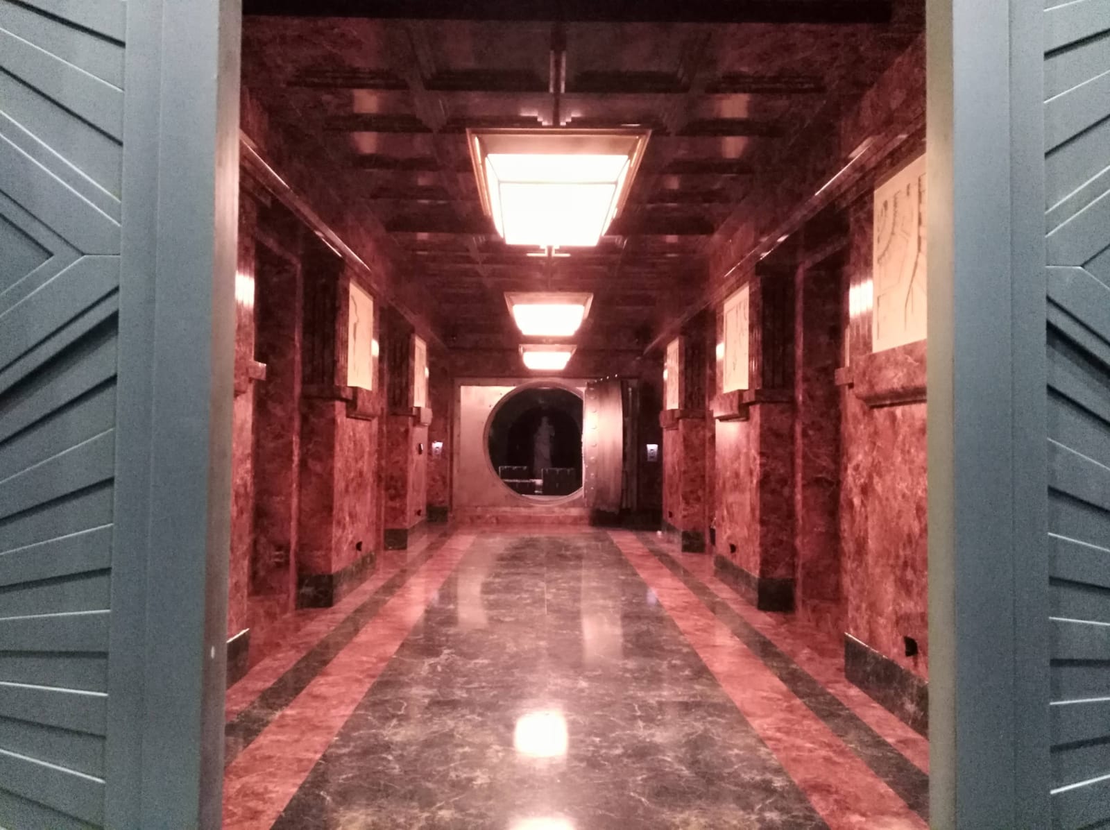 Un largo pasillo con suelos de mármol y una luz de techo.