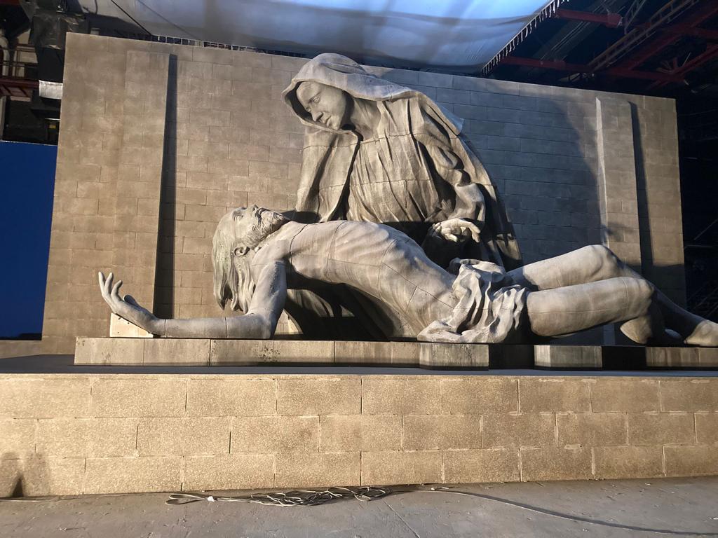 Una estatua de Jesús tendido en el suelo con una mujer parada detrás de él.