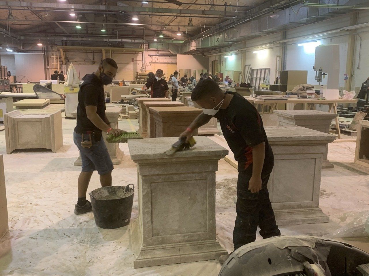 Un hombre que lleva una máscara está limpiando una mesa en una fábrica.