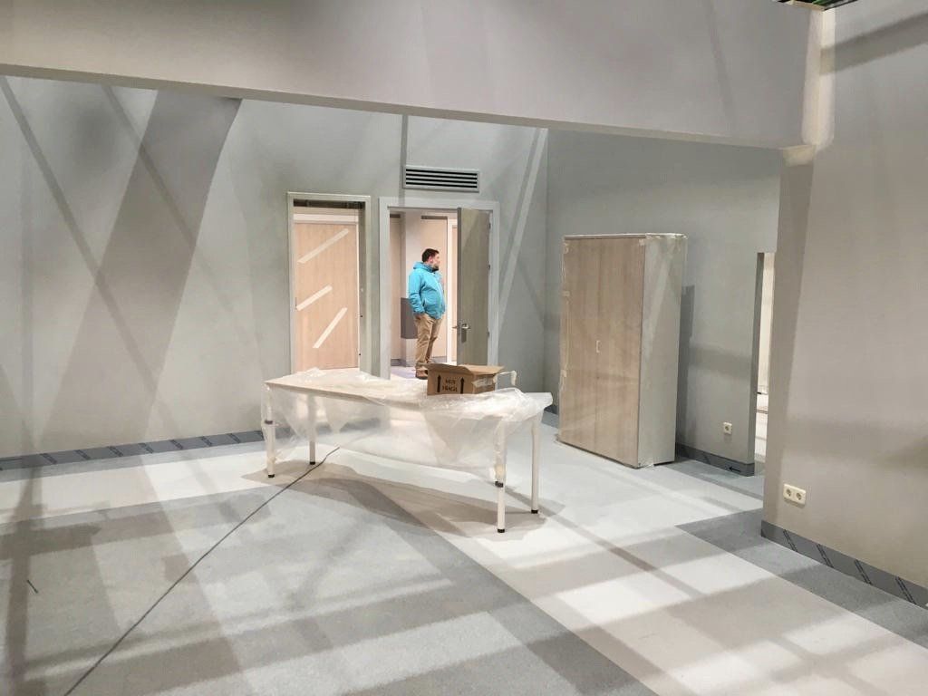 Un hombre está de pie en una habitación con una mesa y armarios.