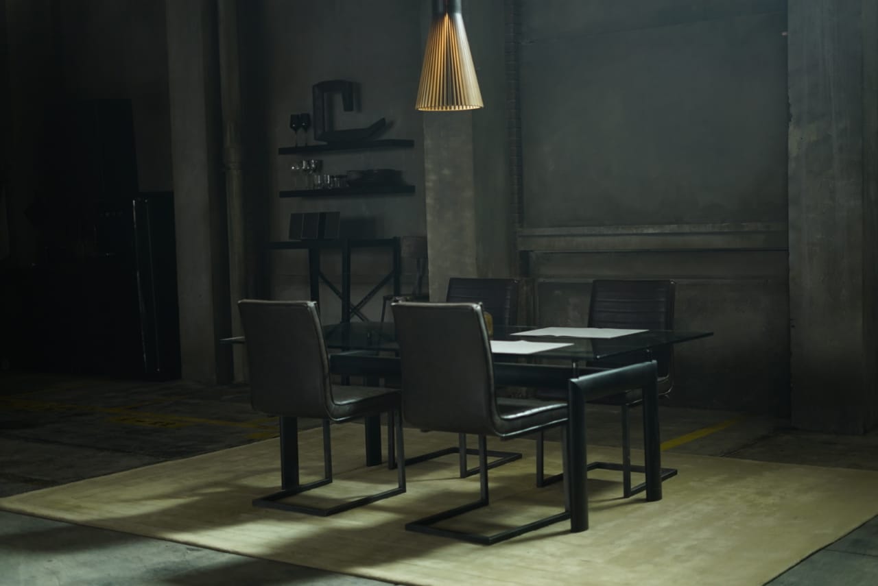 Un comedor con una mesa y sillas en una habitación oscura.