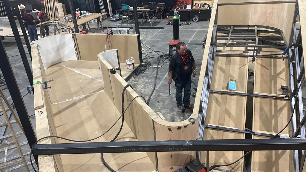 Un hombre está parado en medio de una estructura de madera.