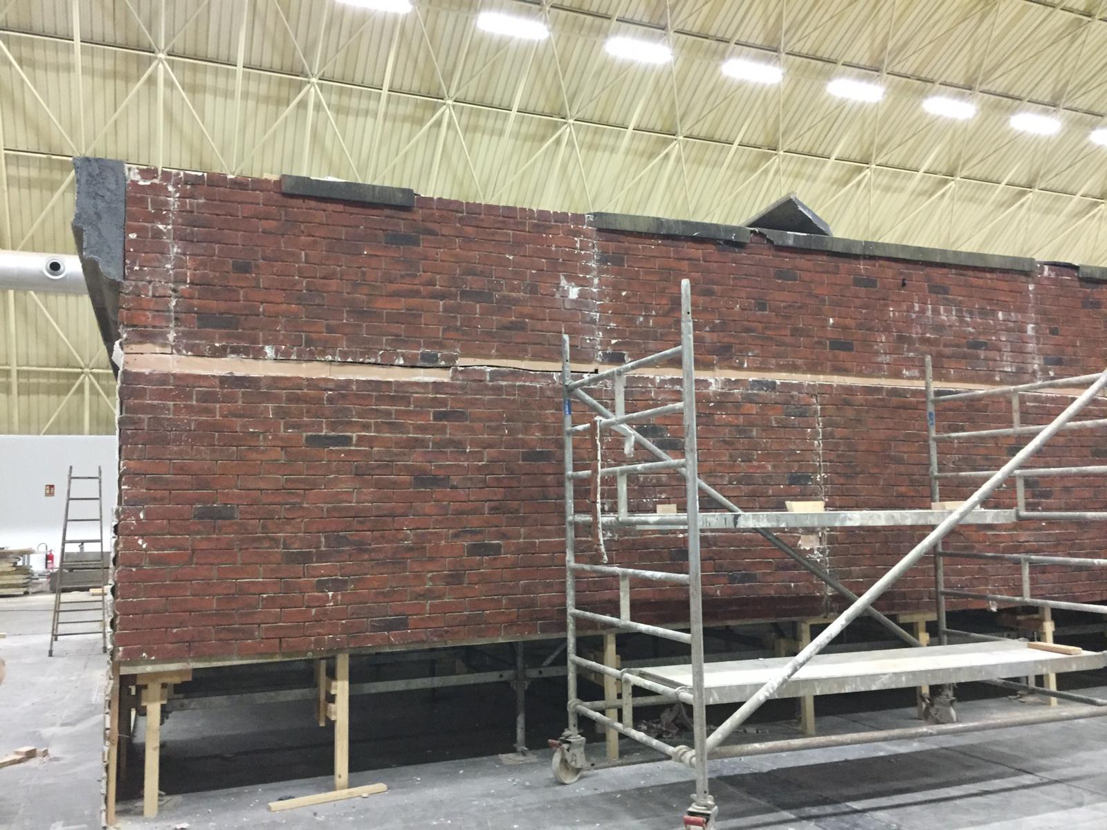 Una pared de ladrillos con andamios a su alrededor en un edificio.