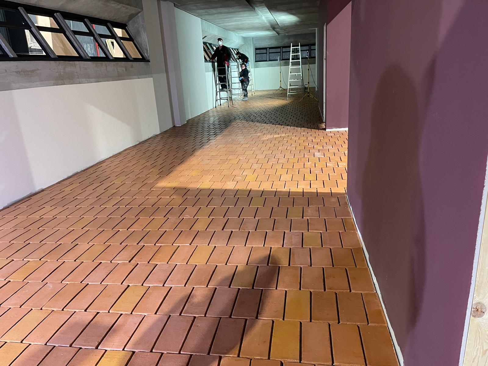 Una habitación con piso de ladrillo y una pared morada.