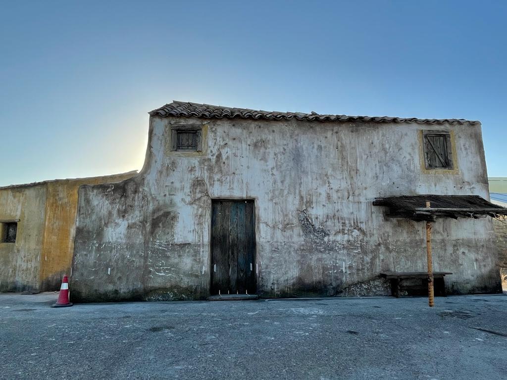 Un edificio viejo con una puerta de madera está sentado en el medio de un estacionamiento.