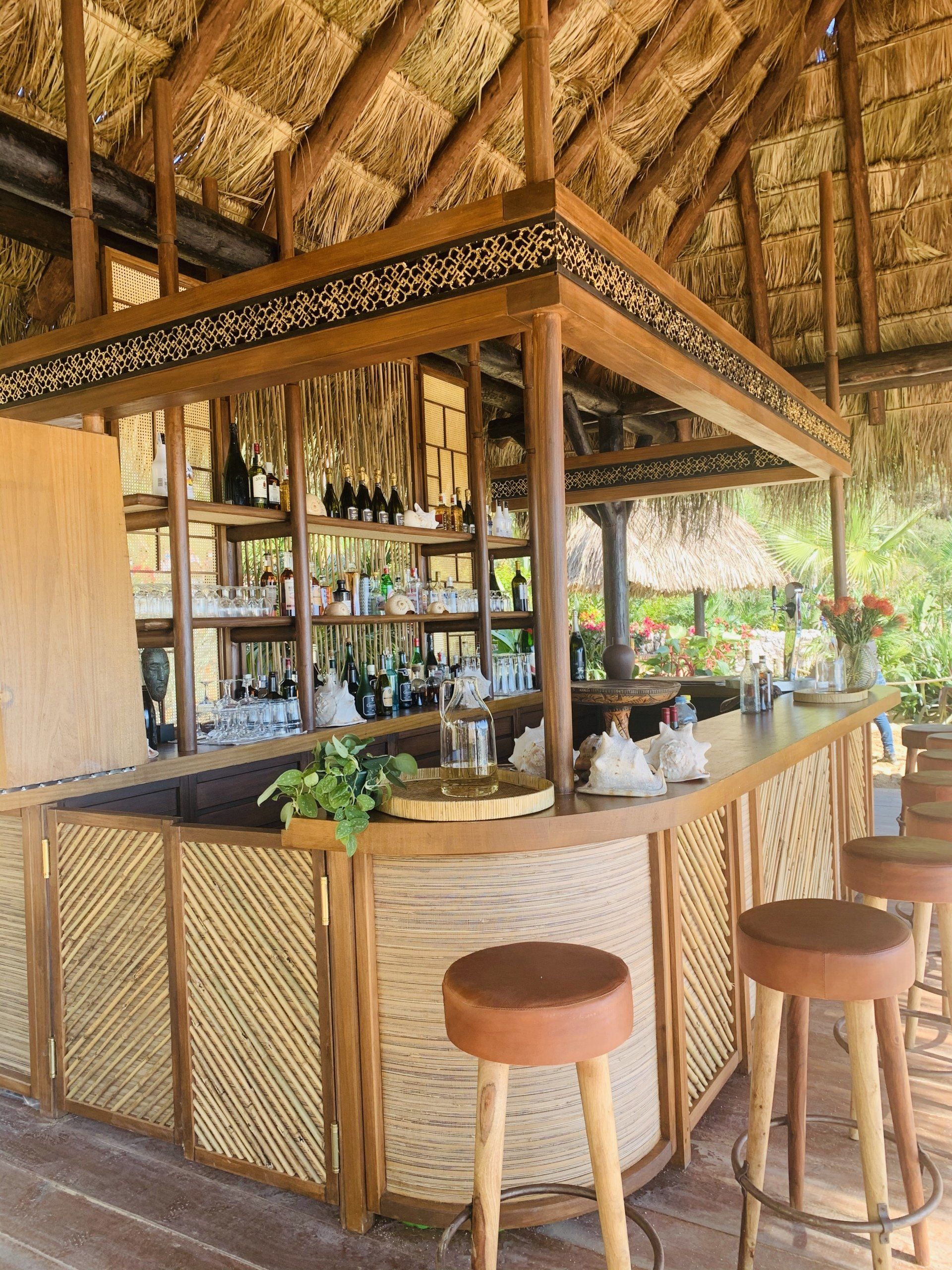Un bar con taburetes y techo de paja