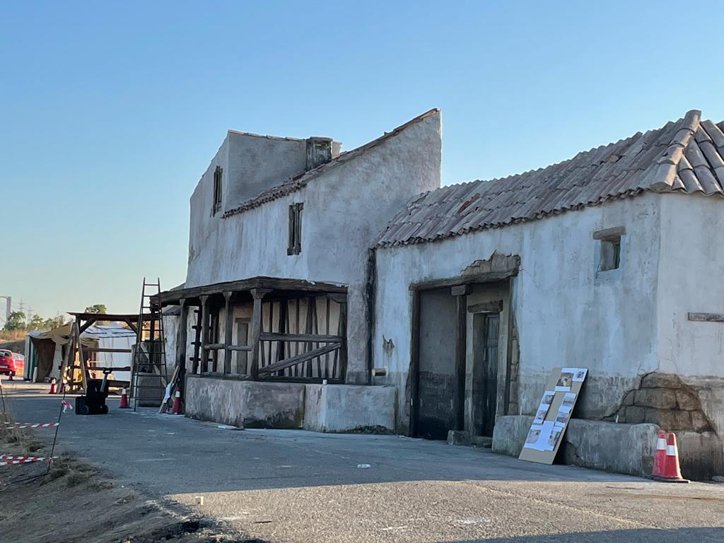 Un gran edificio blanco con techo está situado al costado de una carretera.