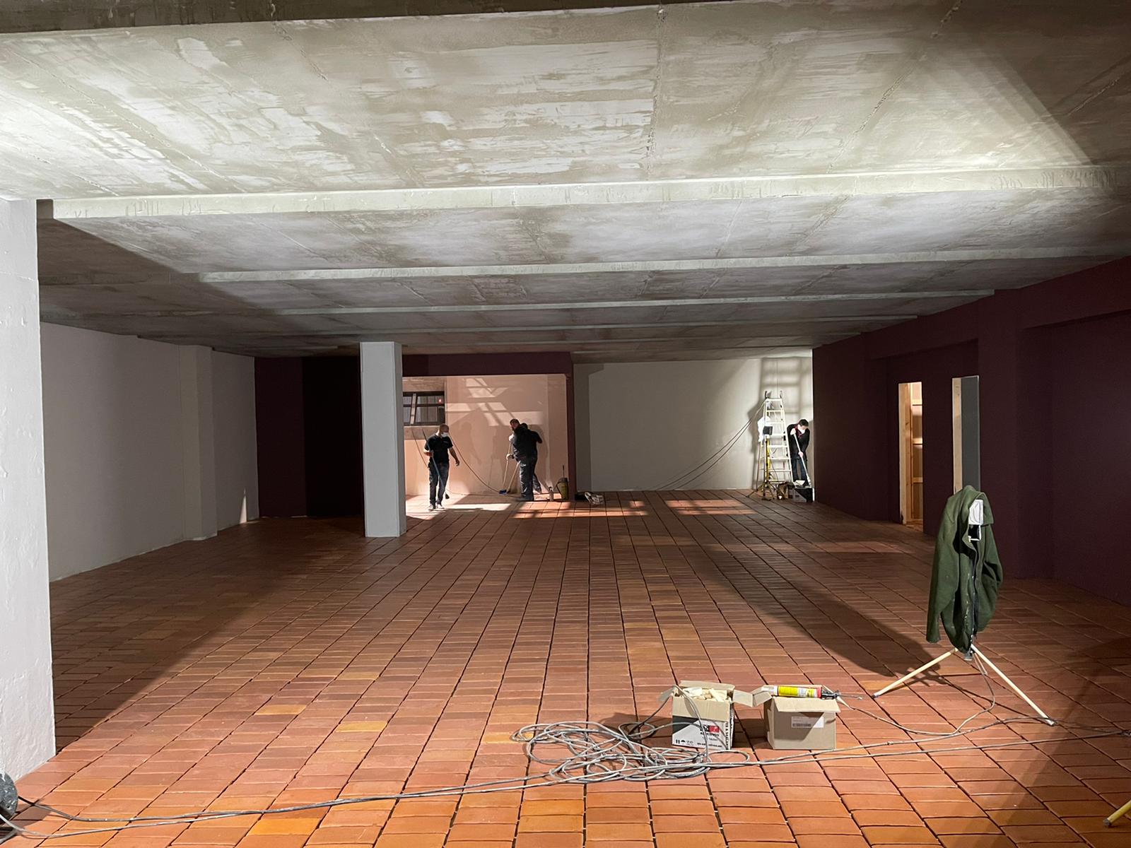 Una gran habitación vacía con suelo de ladrillo y techo de hormigón.