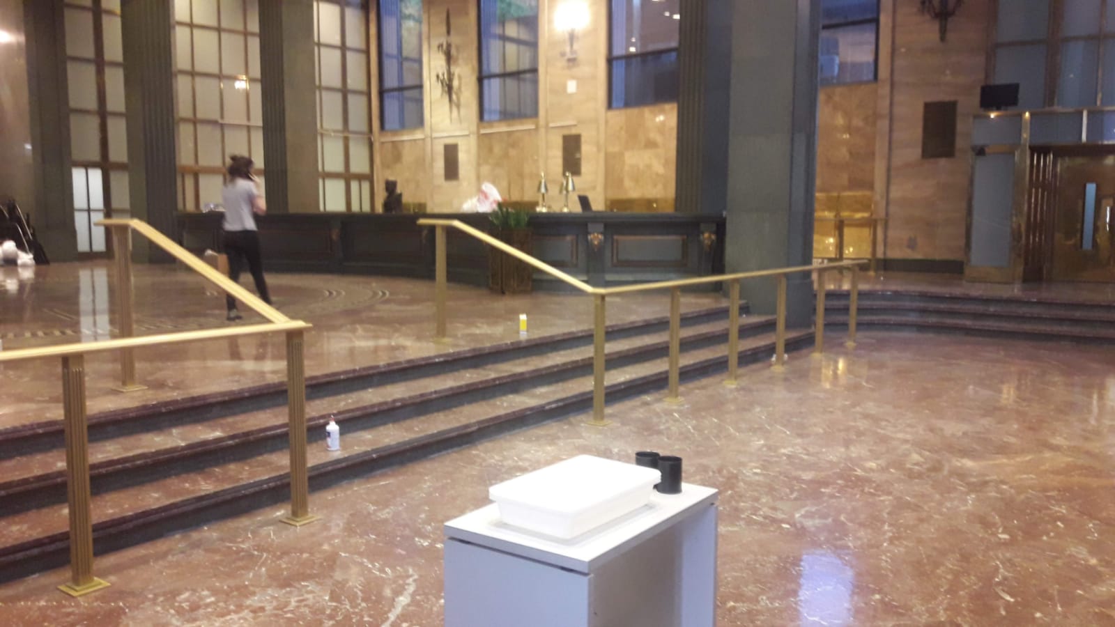 Un vestíbulo vacío con escaleras y una caja blanca en el suelo.