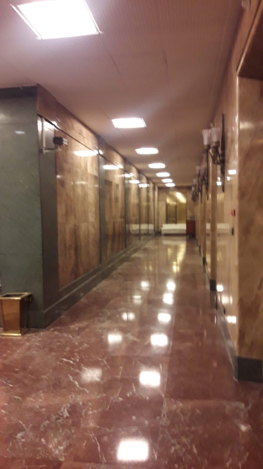 Un largo pasillo con pisos y paredes de mármol en un edificio.