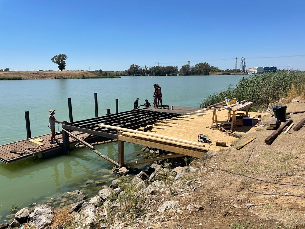 Se está construyendo un muelle de madera en la orilla de un lago.