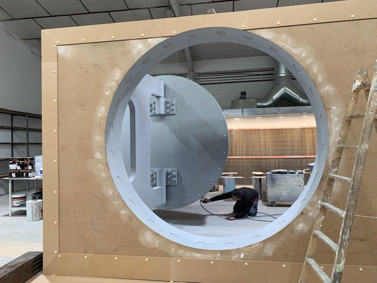 Un hombre está arrodillado frente a una gran puerta redonda.