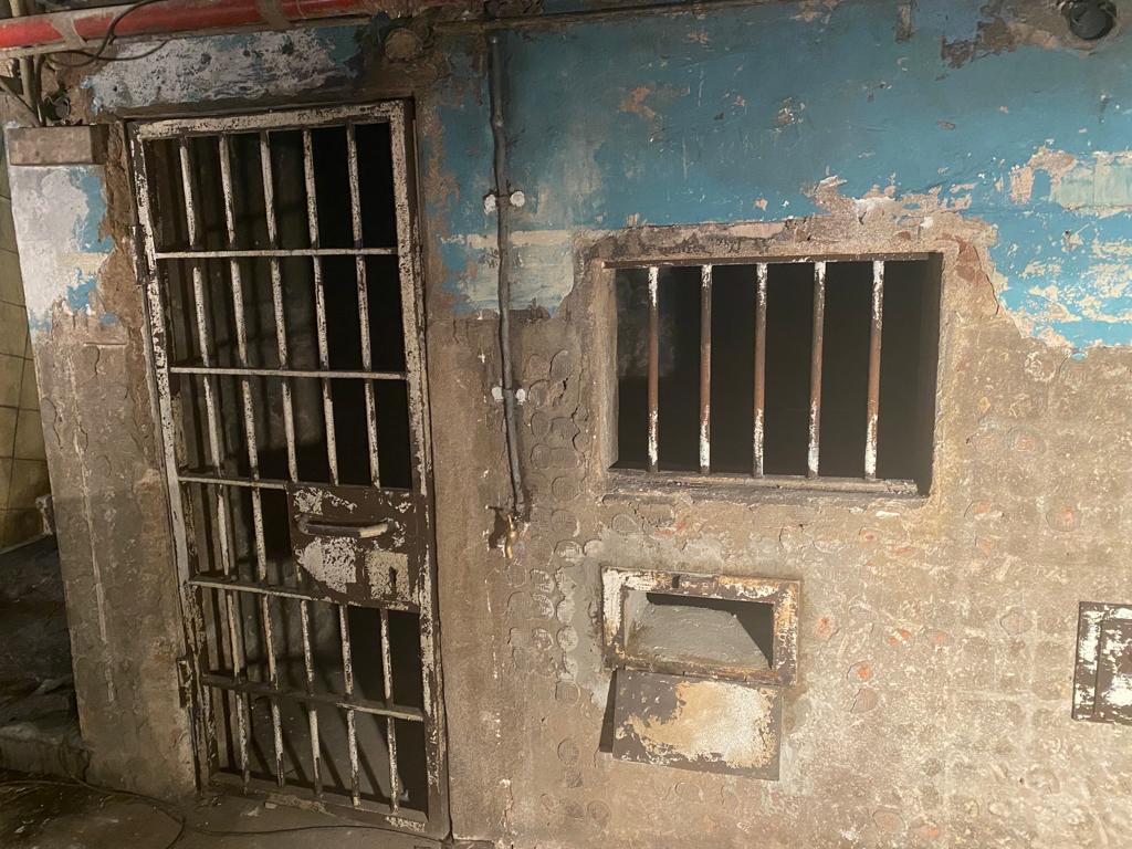 Un edificio antiguo con una puerta de celda de prisión y dos ventanas.