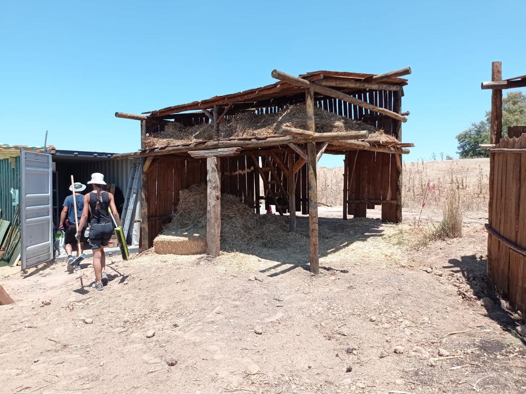Un grupo de personas camina hacia un edificio de madera en el desierto.