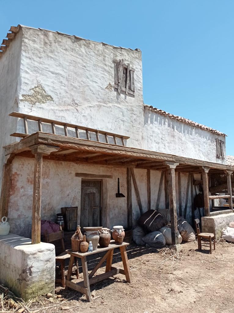 Un edificio blanco con un porche de madera y una mesa de madera delante.
