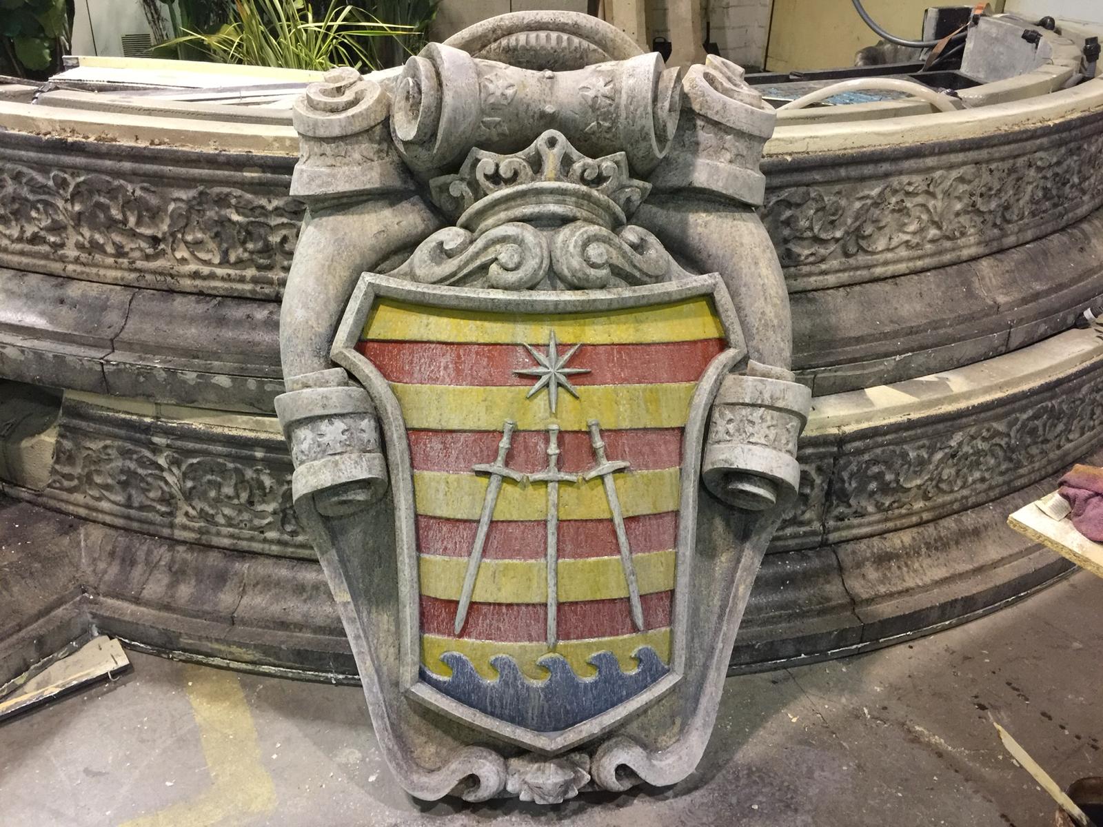 Un escudo de armas está sentado encima de un muro de piedra.