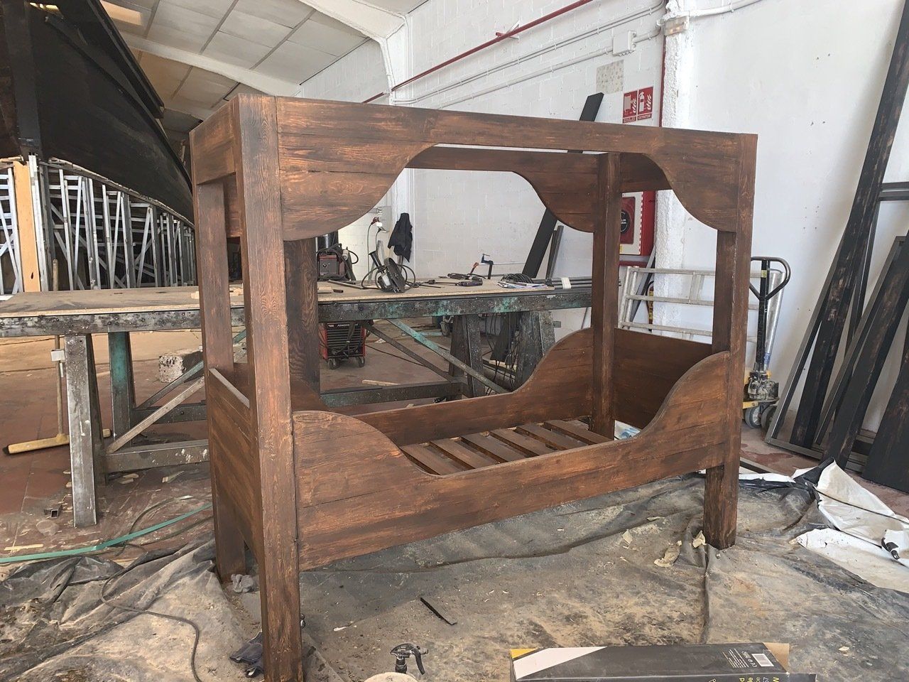 En un taller se está construyendo una cama con dosel de madera.