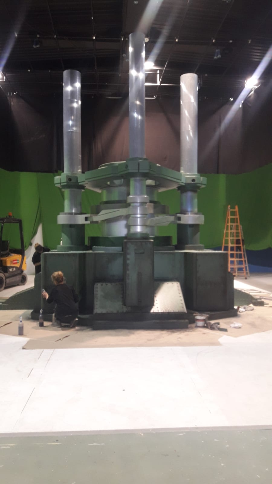 Se está construyendo una gran escultura en una sala grande con una pantalla verde detrás de ella.