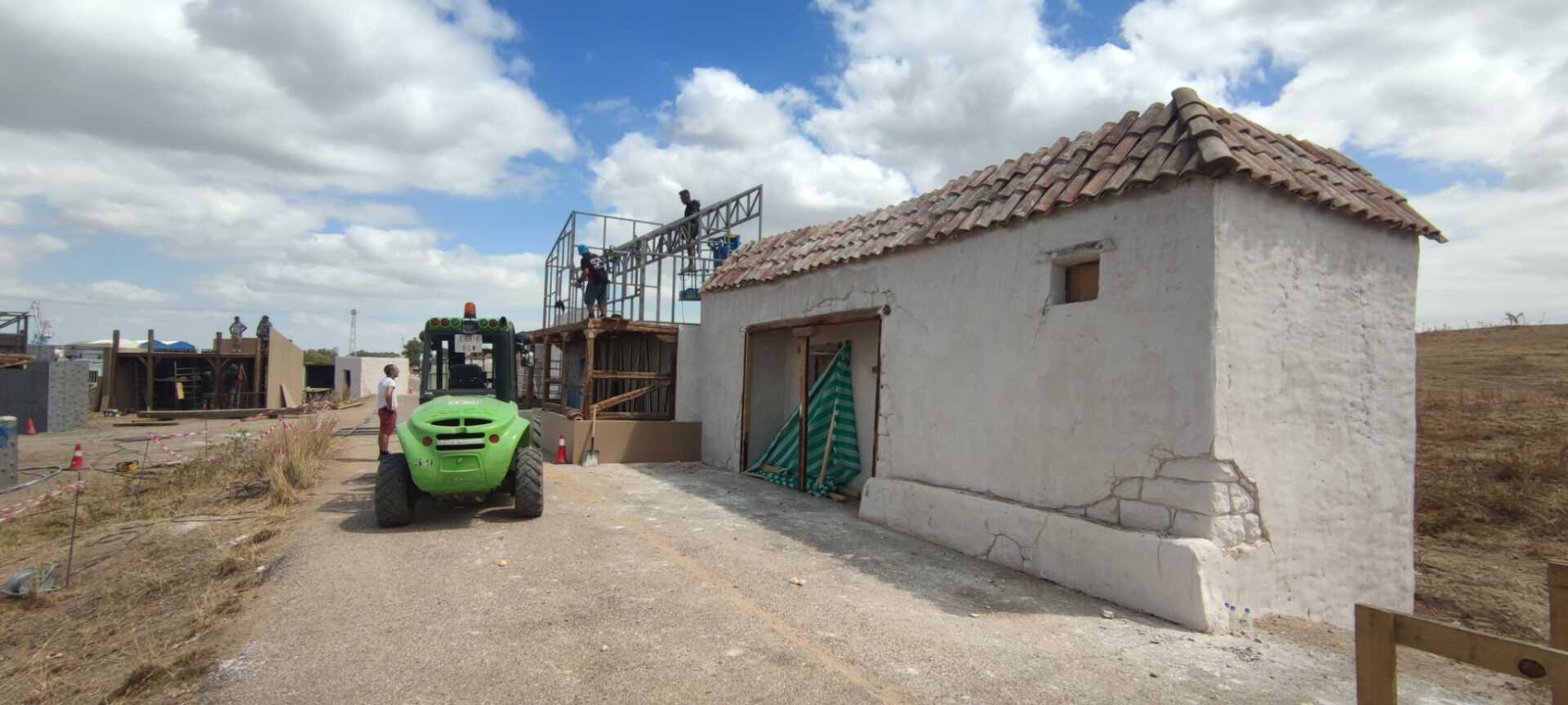 Una carretilla elevadora verde está estacionada frente a un edificio blanco.