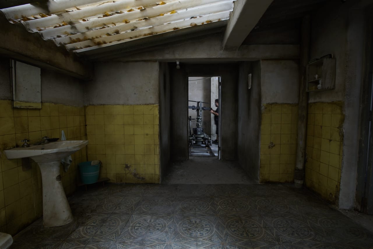 Un baño vacío con azulejos amarillos y un lavabo.