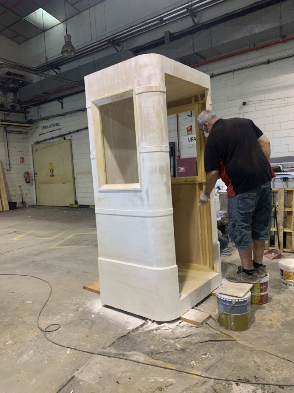 Un hombre está pintando una caja blanca en un almacén.