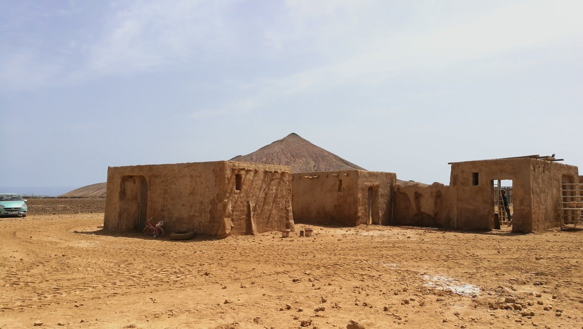 Un edificio en medio de un desierto con una montaña al fondo.