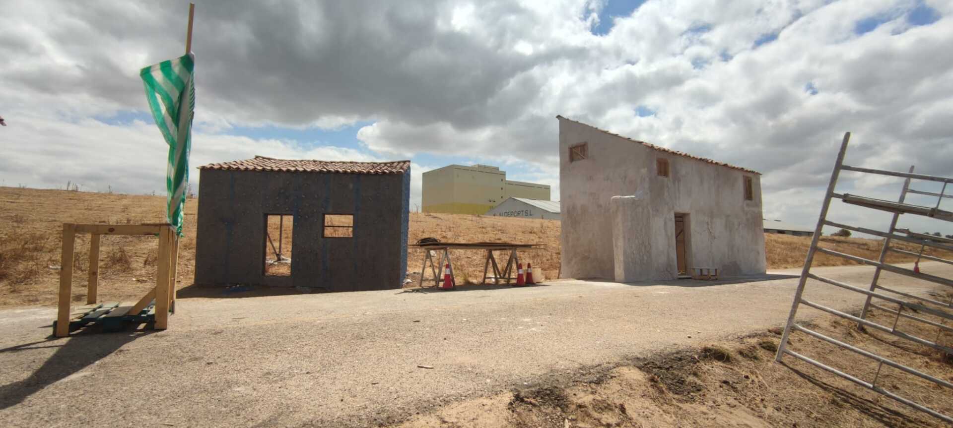 Un grupo de edificios se encuentran encima de un campo de tierra.