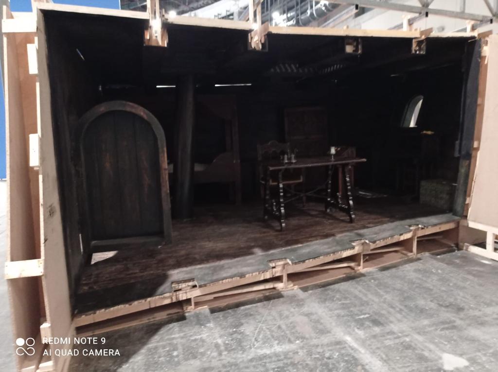 Una caja de madera con una mesa y sillas dentro.