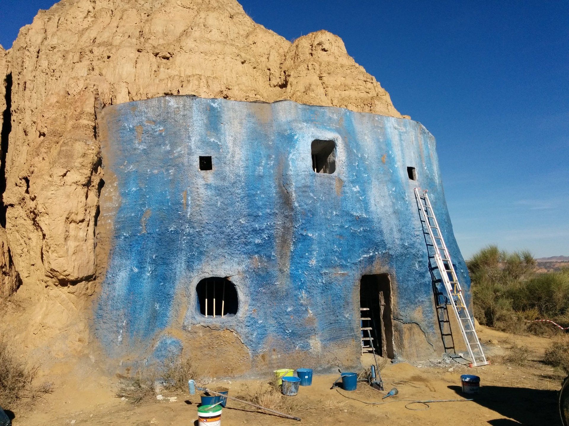 Un edificio azul con una escalera apoyada en él.